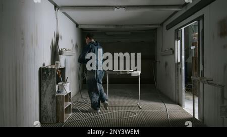 Worker polishes board before painting. Creative. Worker in suit grinds board in special room. Grinding of product before painting in painting room. Stock Photo