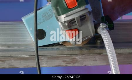 Close-up of hand cutter with water. Creative. Electric jigsaw for manual trimming of hard plates. Manual circular saw with modern water supply technol Stock Photo