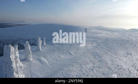 Landscape in sub-zero temperatures from above. Clip.Snowy empty mountains with frozen hills and trees are visible against a bright sky. High quality F Stock Photo