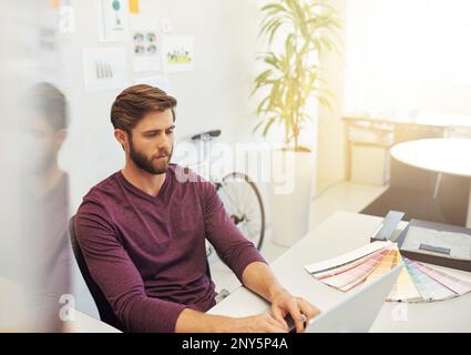 Putting in the hours. a young architect working on his latop. Stock Photo