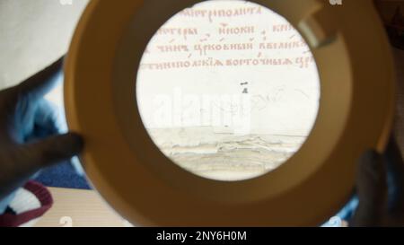 A large magnifying glass lamp that shines on an old letter. Stock footage.An old paper covered with Old Russian letters in the archive, which is exami Stock Photo