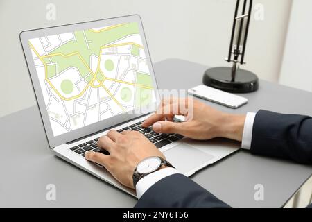 Man analyzing cadastral map on laptop at table, closeup Stock Photo