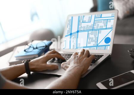 Man analyzing cadastral map on laptop at table, closeup Stock Photo