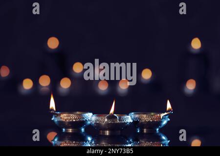 Lit diyas on table against blurred lights. Diwali lamps Stock Photo