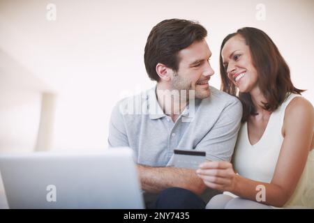 We make a great team. A married couple being affectionate while doing their online banking together. Stock Photo