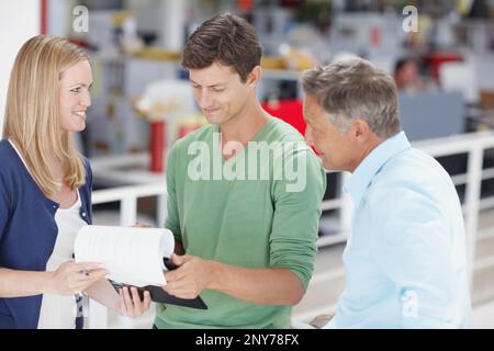 Working together as a team. Three work colleagues discussing something work related. Stock Photo