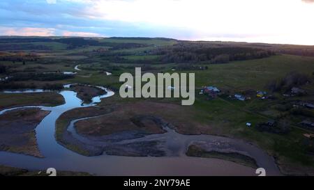 Aerial view of summer fields and curving narrow rivers. Clip. Wet ground and green meadows on a blue cloudy sky background Stock Photo