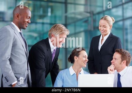 Business team in discussion. Group of multi ethnic business people discussing while using laptop. Stock Photo