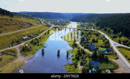 Arial view of a small town crossed by a river with a bridge. Clip. Ecological place, living in the countryside Stock Photo