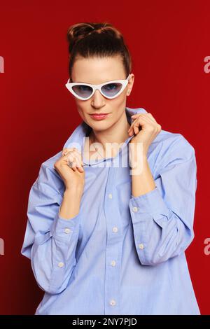 Medium closeup portrait of pretty woman spreading the collar of her shirt to the sides Stock Photo
