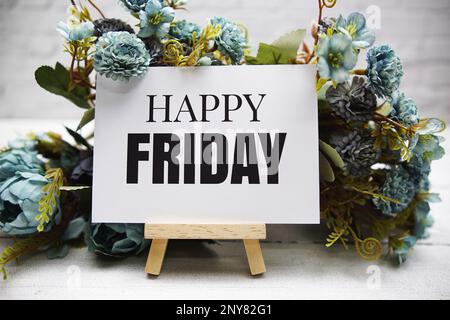 Happy Friday text on wooden easel standing on white brick wall and wooden background Stock Photo