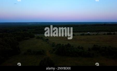 Autumn dawn in the field. Clip. Flying above the road, farm fields and growing trees, beauty of nature on sunset pink and blue sky background Stock Photo