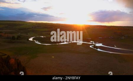 Autumn dawn in the field. Clip. Flying above the curved river, farm fields and growing trees, beauty of nature on sunset pink and blue sky background Stock Photo