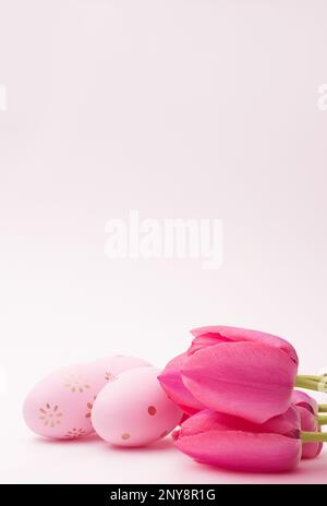 Colored eggs  with tulips on pink background. Easter. Vertical. Copy space Stock Photo