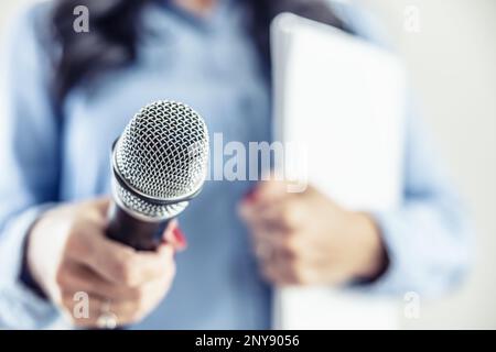 Investigative journalist with microphone in other hand notebook - Close up. Stock Photo