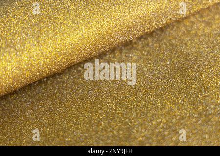Golden wave shiny glitter paper texture. Shining luxurious fabric. Glimmering golden color, christmas background. Stock Photo