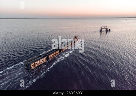 Old train rides on the railway laid in the water through the salt lake. train travels from water. Mined salt in Lake Burlin. Altai. Russia. Bursolith. Stock Photo