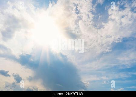 light from heaven. Sun and clouds. ecrice the rays of the sun shining through the feathery white clouds in the blue sky. Beautiful background. Stock Photo