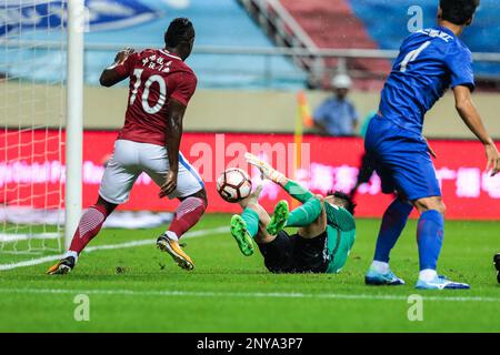 Cameroonian football player Christian Bassogog, left, of Henan Jianye, shoots against Shanghai Greenland Shenhua in their 24th round match during the 2017 Chinese Football Association Super League (CSL) in Shanghai, China, 10 September 2017.(Imaginechina via AP Images)