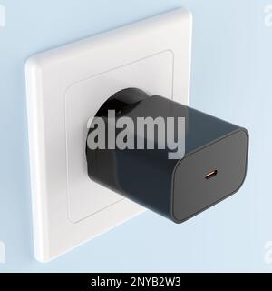Black smartphone charger plug in the electric socket on a wall Stock Photo