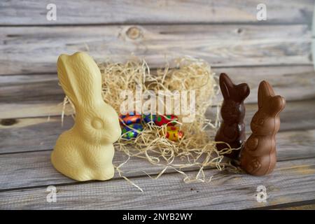 Chocolate Easter bunnies atop a pile of hay with chocolate eggs on the background Stock Photo