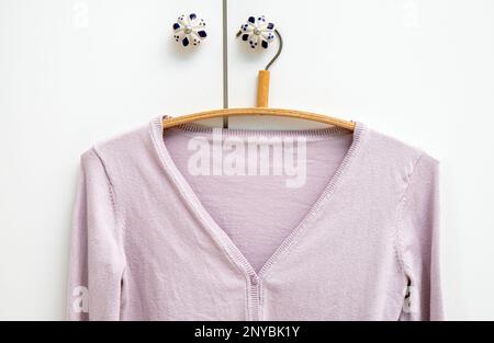 Stretched Out from shoulders cardigan hanging on bad shape hanger in home room. How to avoid fabric stretch marks concept. Stock Photo