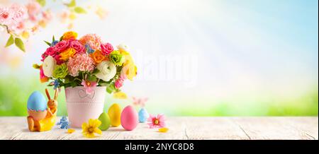 Easter composition with spring flowers in vase, bunny and Easter eggs on wooden table. Easter still life with copy space. Banner Stock Photo