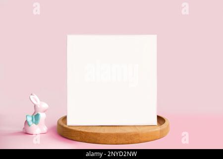 Blank Greeting Card, Invitation Mockup. Front view Easter Composition with Ceramic Bunny on Table. Copy space. Paper Spring Mock up Minimal Business B Stock Photo