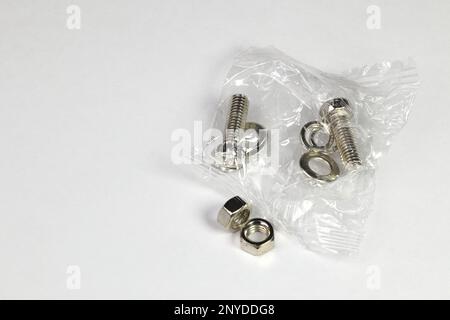 spare stainless steel screw, nuts and bolts or iron nails in plastic bag isolated on white background. Stock Photo