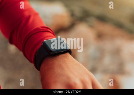 Man Using A Digital Smartwatch During Workout. Closeup View Of Man's Hands Checking An App In Smartwatch. Close-up Of A Clock That Shows Steps Stock Photo