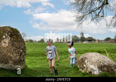 Children play amongst Long Meg and Her Daughters stone circle standing stones at Little Salkeld, near Penrith, Eden Valley, Cumbria. Stock Photo