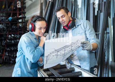 male and female workers looking at blueprint in workshop Stock Photo