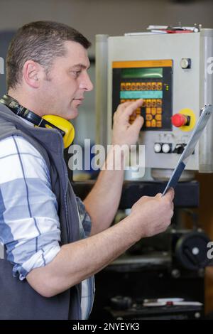 factory worker is programming a cnc milling machine Stock Photo