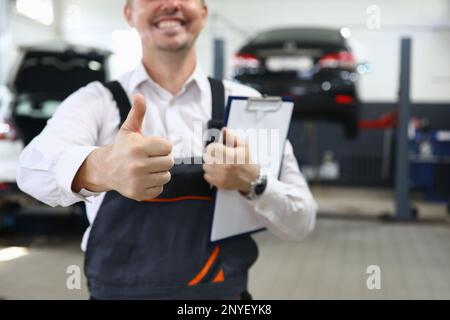 Portrait of male mechanic showing thumbs up in car service Stock Photo