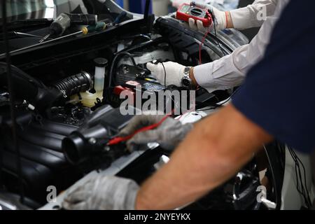 Professional auto mechanic works in a car service and tests operation of engine with tester Stock Photo