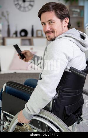 happy man on wheelchair using smartphone at home Stock Photo