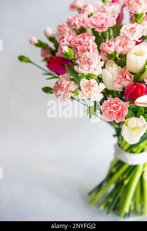 Beautiful carnation and tulip bouquet on concrete background Stock Photo