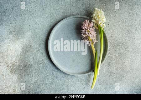 From above spring table setting with hyacinth flower near ceramic plate on grey concrete table for festive dinner Stock Photo