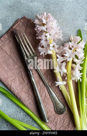 From above spring table setting with hyacinth flower near cutlery on grey concrete table for festive dinner Stock Photo