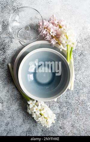 From above spring table setting with hyacinth flower near ceramic plate and cutlery on grey concrete table for festive dinner Stock Photo