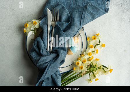 From above spring table setting with ceramic plate near daffodil flowers on concrete background Stock Photo