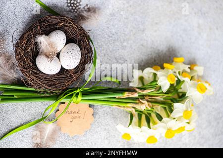 From above easter card concept with nest with eggs and daffodil flowers in bouquet Stock Photo