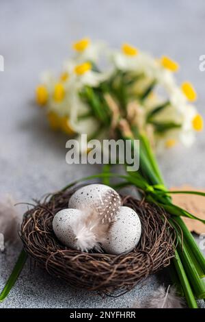 From above easter card concept with nest with eggs and daffodil flowers in bouquet Stock Photo