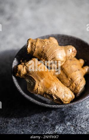 Black stone bowl with ginger roots on concrete kitchen table Stock Photo
