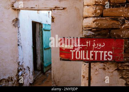 Red signboard with inscription on shabby brick wall of weathered old building in Mauritania Stock Photo