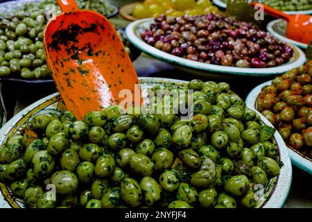 From above of ripe green olives with scoop in metal bowl placed on stall in local market at Mauritania Africa Stock Photo