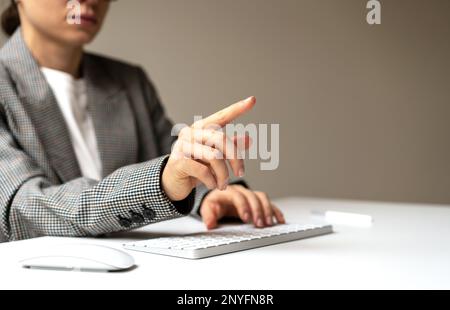 Woman person sitting at the desk working on computer touching virtual screen with finger. Stock Photo