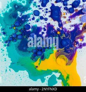 Backdrop with top view of abstract vivid blue and orange inky circles placed on blurred multicolored transparent surface Stock Photo