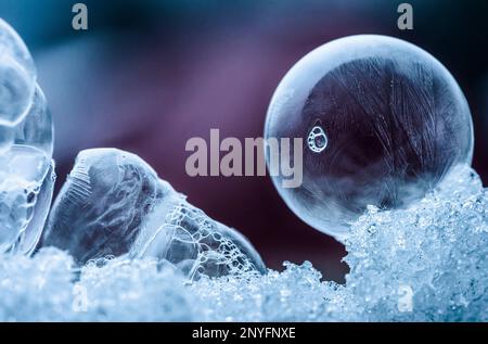 Amazing abstract backdrop with closeup transparent soap bubbles frozen on pile of crushed ice against blurred purple surface Stock Photo