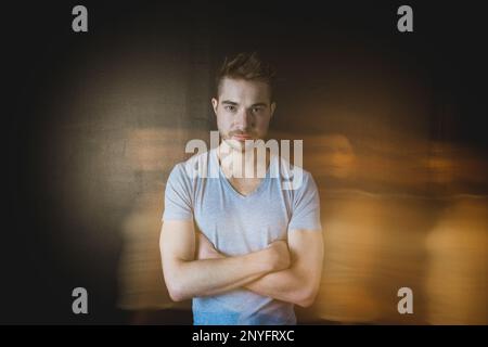 Silhouette of blurred female walking in front of handsome guy keeping arms crossed Stock Photo
